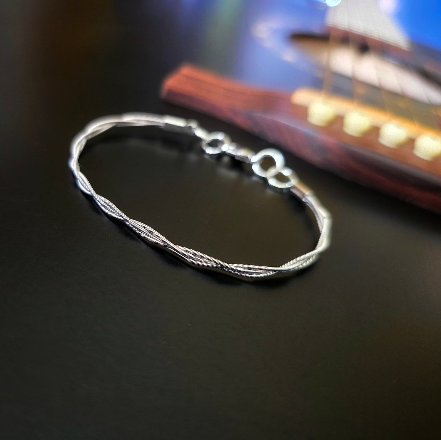 Simple upcycled guitar string braided bracelet on black guitar