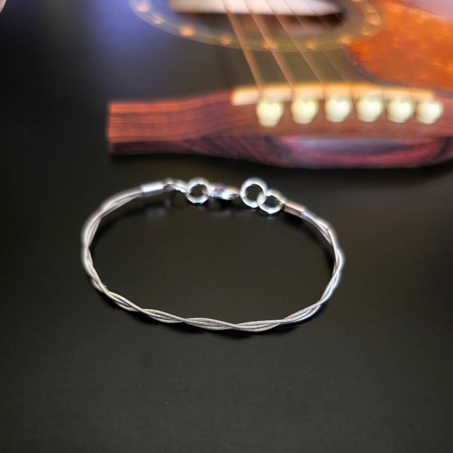Simple upcycled guitar string braided bracelet on black guitar