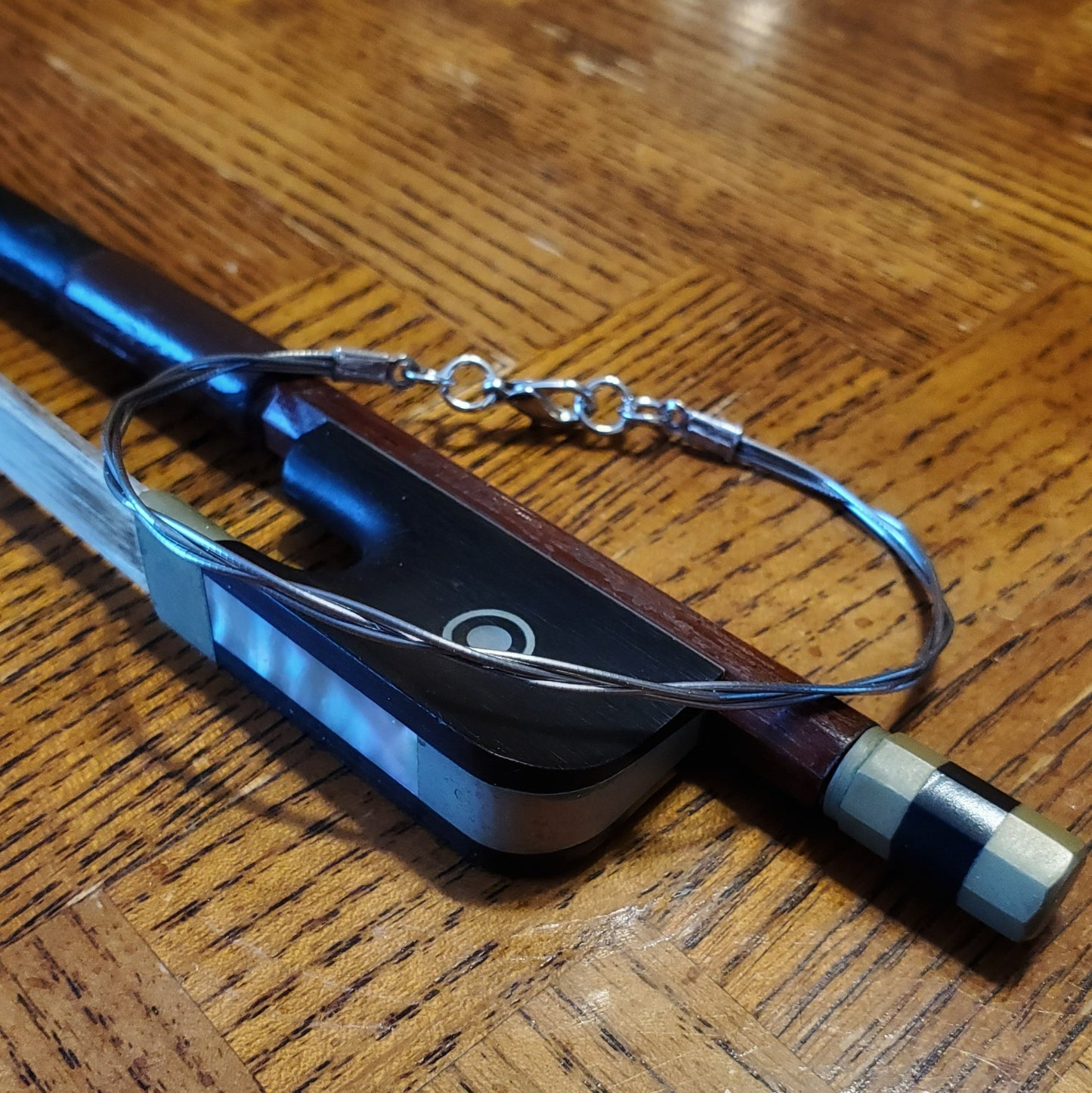 a bracelet made from upcycled violin strings lying on a bow