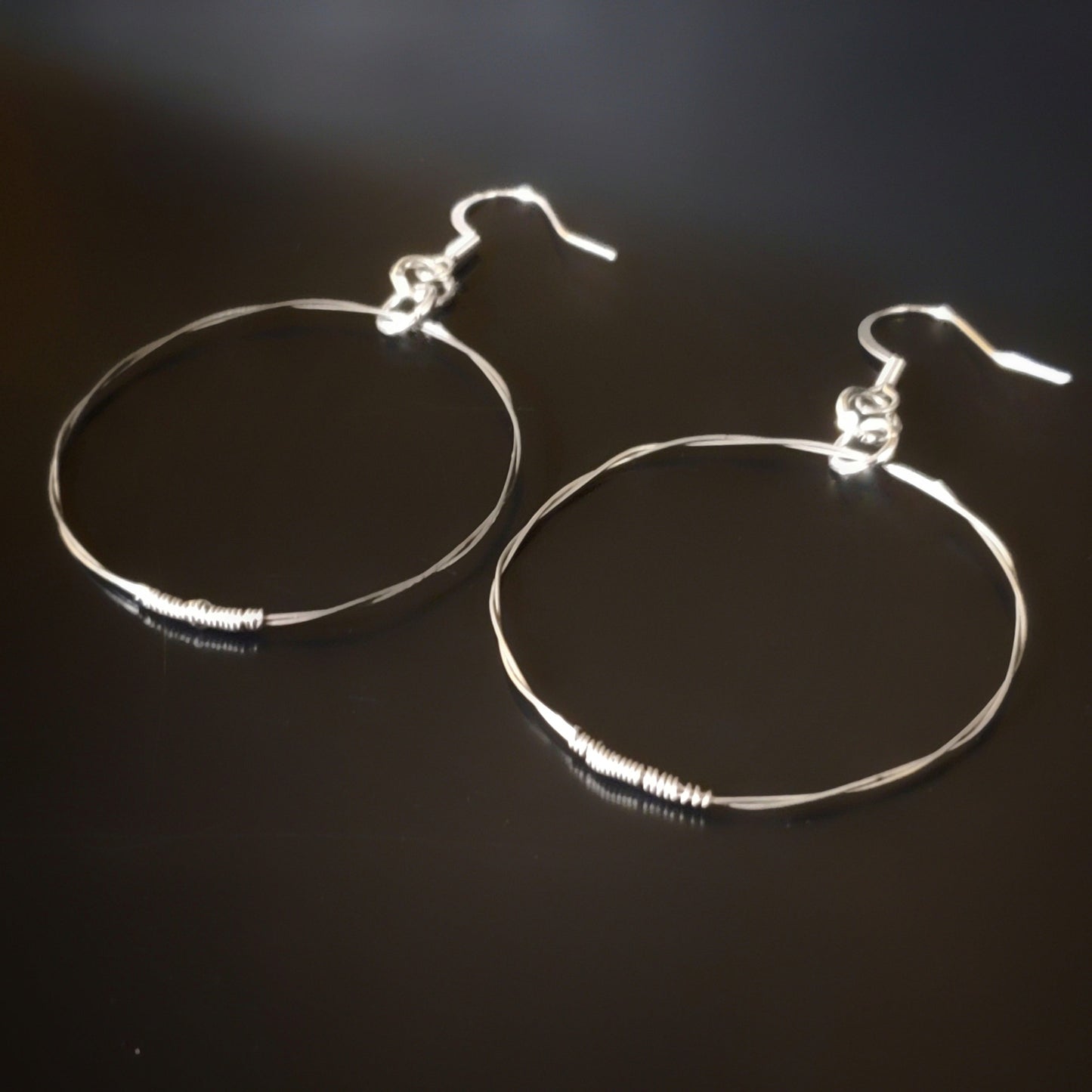 silver coloured hoop style earrings made from upcycled guitar strings 