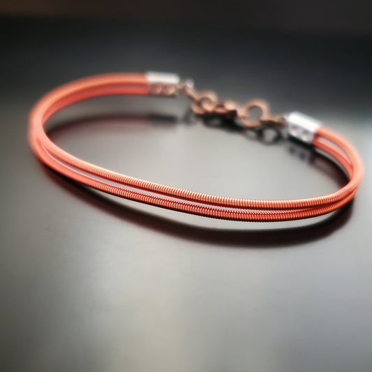 clasp style bracelet made from orange upcycled harp strings