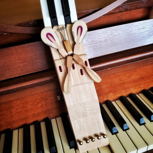 key holder made from 5 upcycled piano keys on the keyholder is a butterfly design made from piano keys and other parts - the key holder is sitting on a piano keyboard