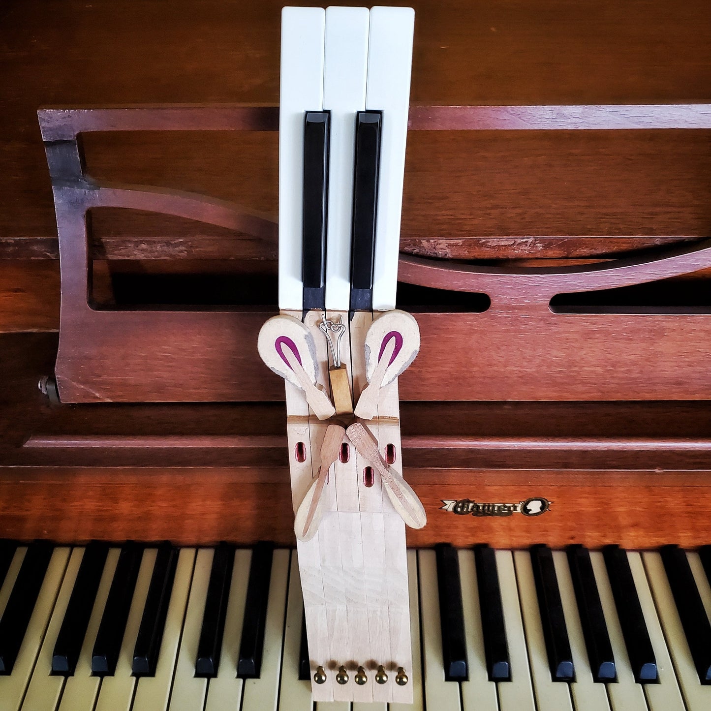 key holder made from 5 upcycled piano keys on the keyholder is a butterfly design made from piano keys and other parts - the key holder is sitting on a piano keyboard