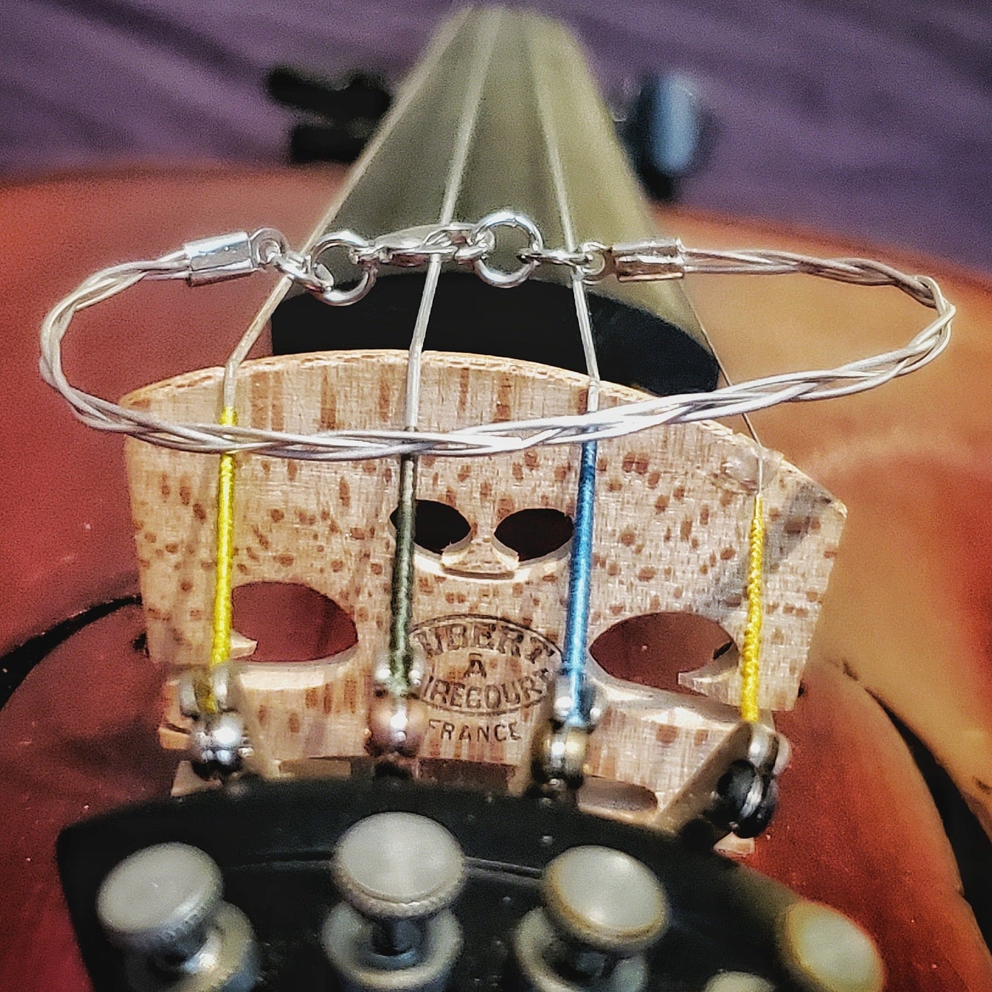 silver coloured violin string bracelet made from upcycled violin strings sitting on a violin