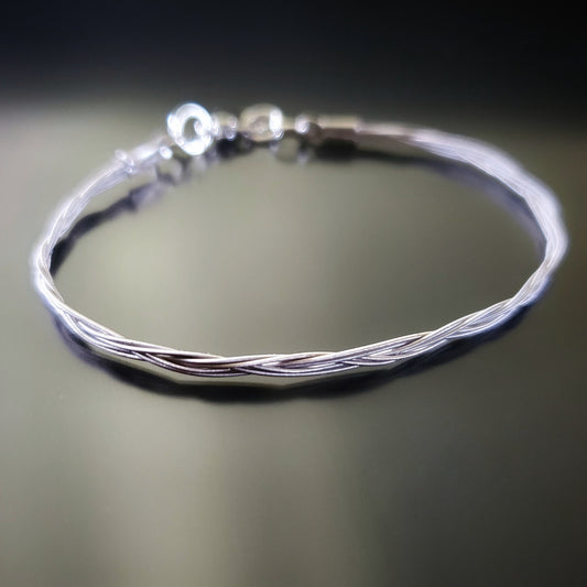 silver banjo string bracelet on a black background