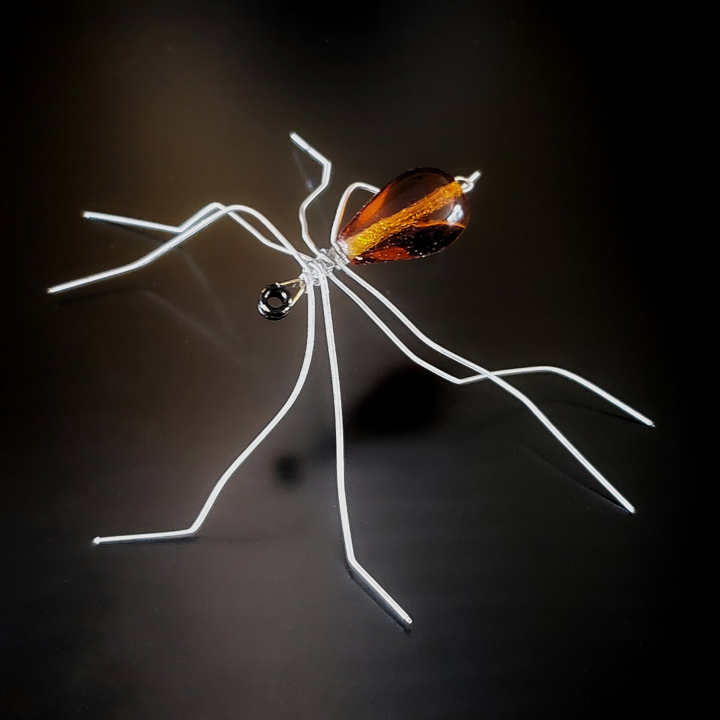 spider sculpture made from upcycled guitar strings and an orange glass bead