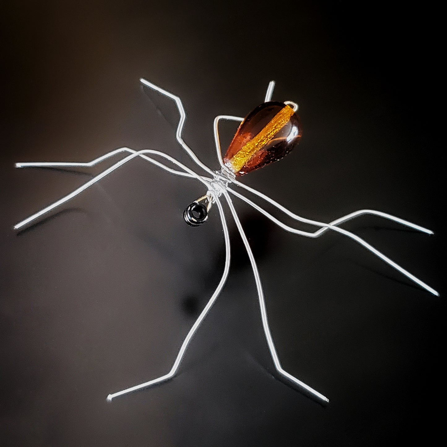 spider sculpture made from upcycled guitar strings and an orange glass bead