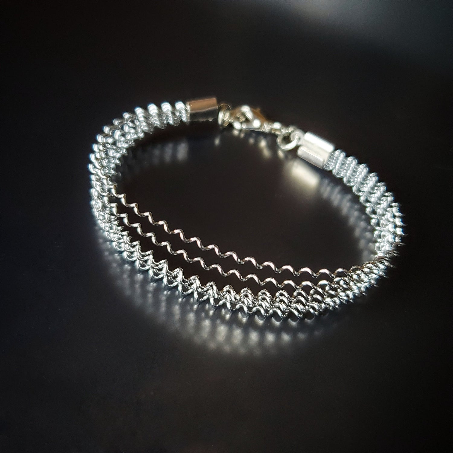 silver coloured clasp style bracelet made from a series of upcycled snare drum strings