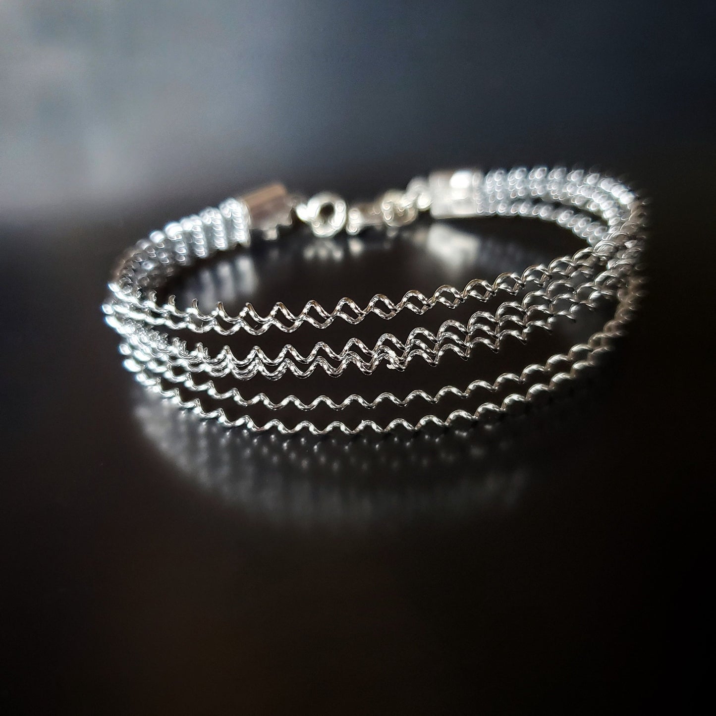 silver coloured clasp style bracelet made from a series of upcycled snare drum strings
