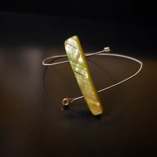 spiral style bangle bracelet made from an upcycled guitar string and a piece of shell in the shape of a rectagle