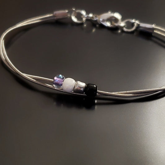 silver coloures clasp style bracelet with 4 glass beads representing the asexual pride flag (black, grey, white & purple)
