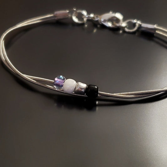 silver coloures clasp style bracelet with 4 glass beads representing the asexual pride flag (black, grey, white & purple) 