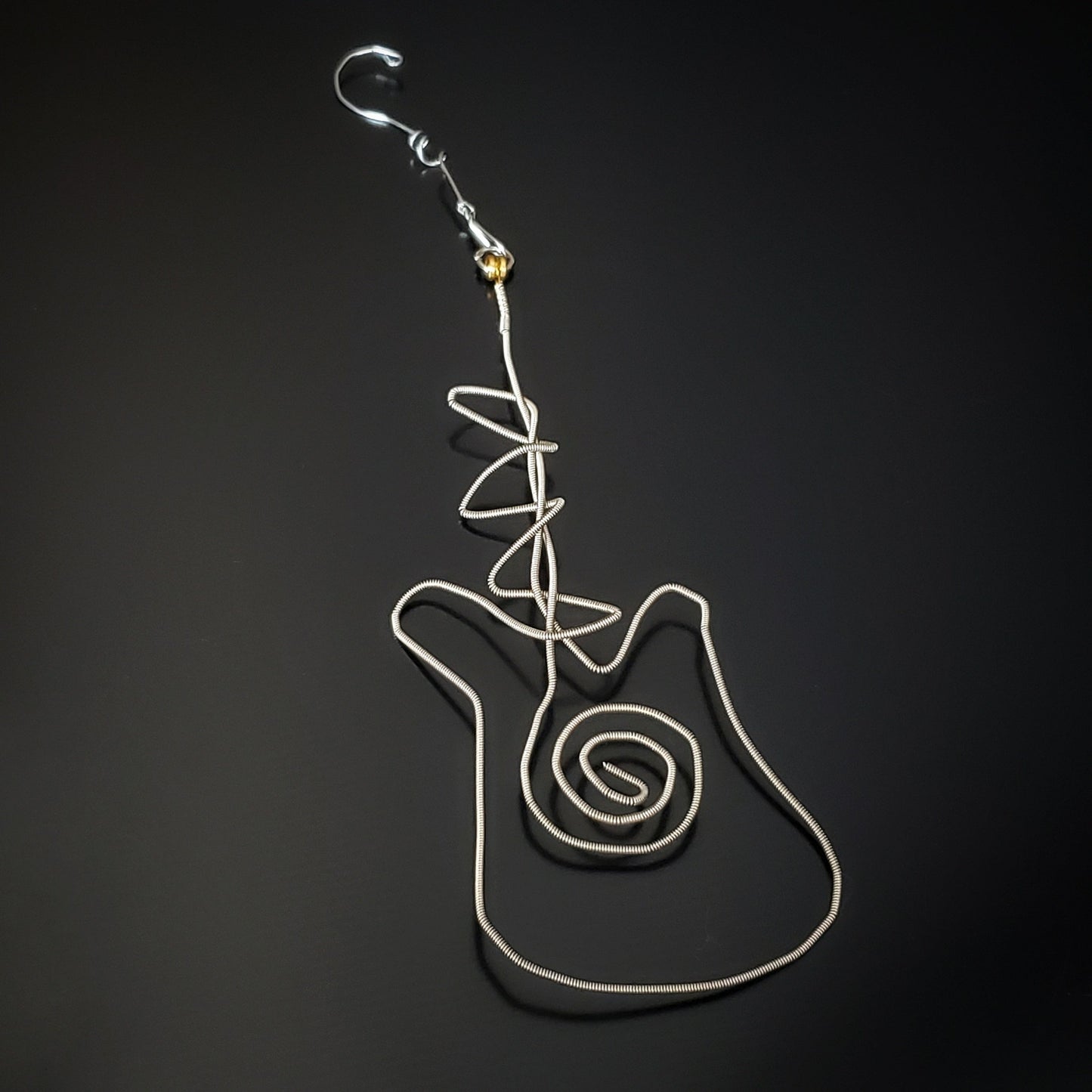 Christmas decoration in the shape of a guitar made from an upcycled guitar string next to a blue guitar pick