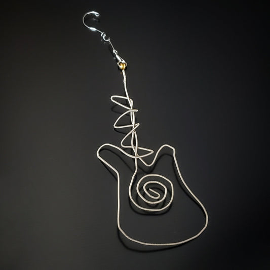 Christmas decoration in the shape of a guitar made from an upcycled guitar string next to a blue guitar pick