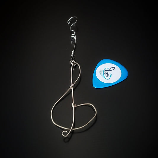 Christmas ornament in the shape of a treble clef, made from an upcycled guitar string - on the left is a blue guitar pick