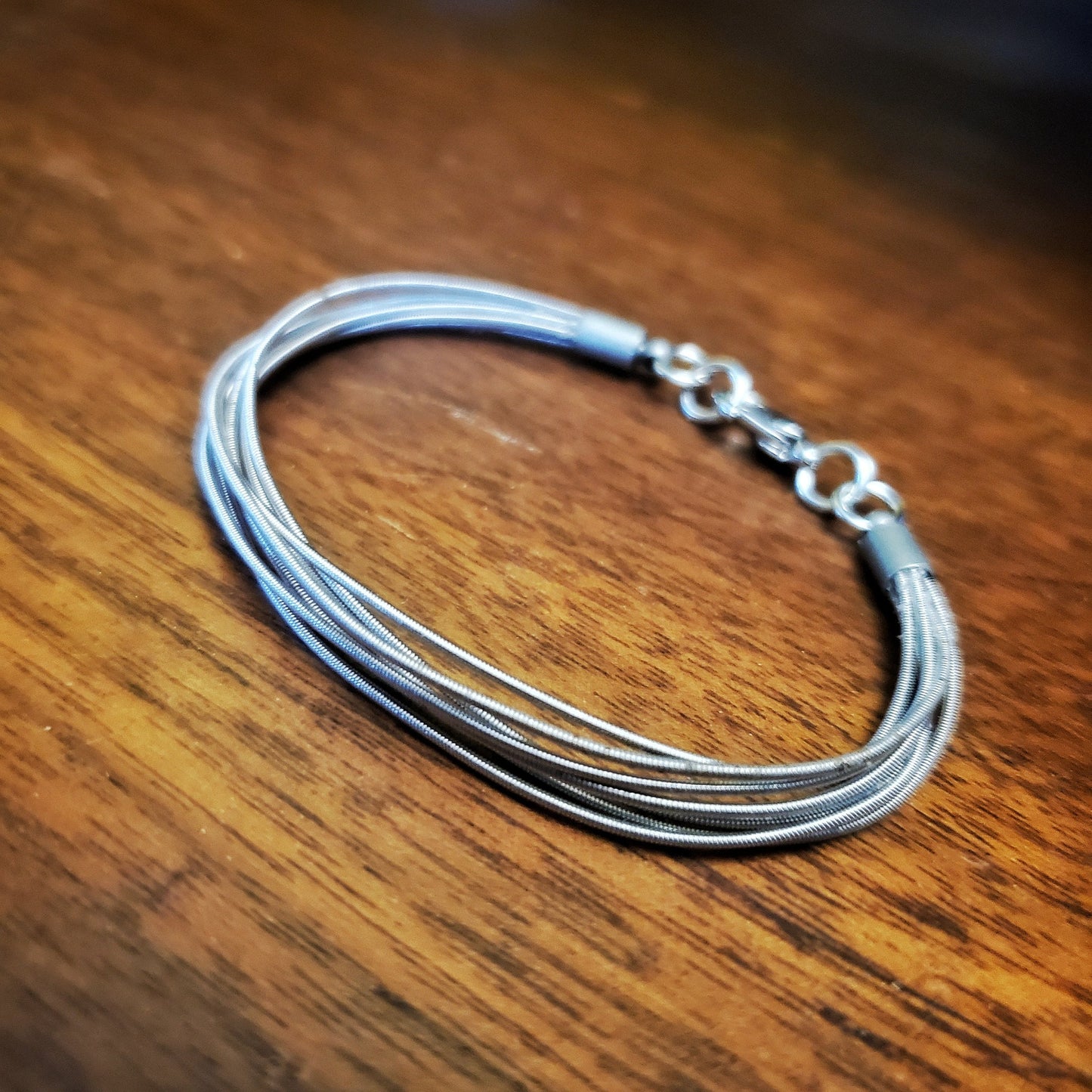 multistrand guitar string clasp style bracelet - wood coloured background