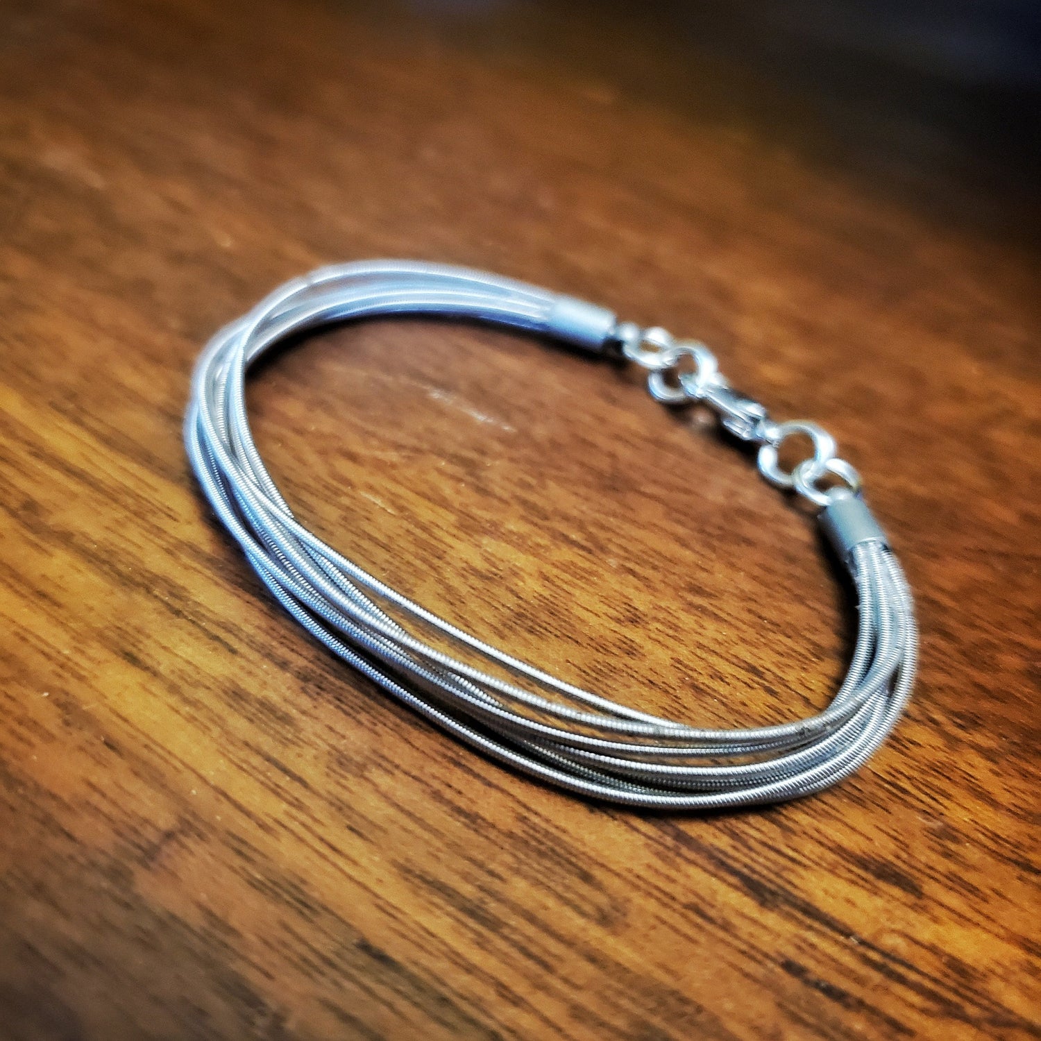 multistrand guitar string clasp style bracelet - wood coloured background