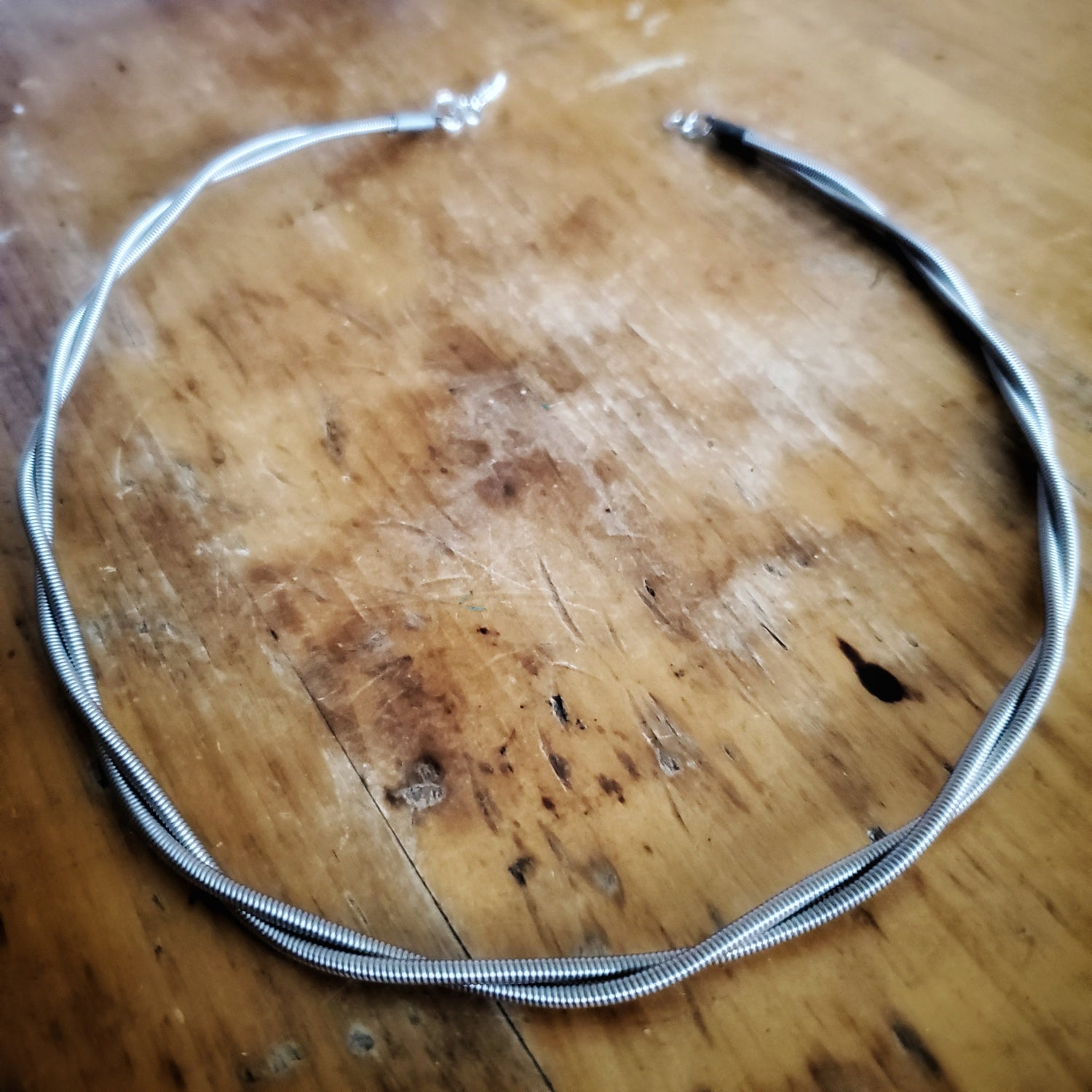 chain made from an upcycled electric bass guitar strings, wood background