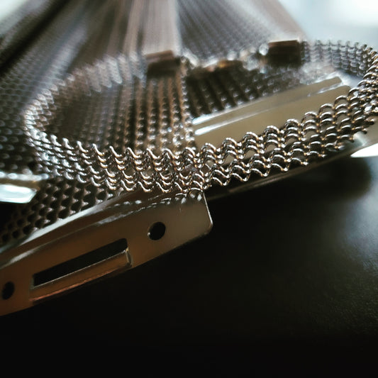 Unisex bracelet made from upcycled snare drum strings sitting on a pile of snare drum strings. 