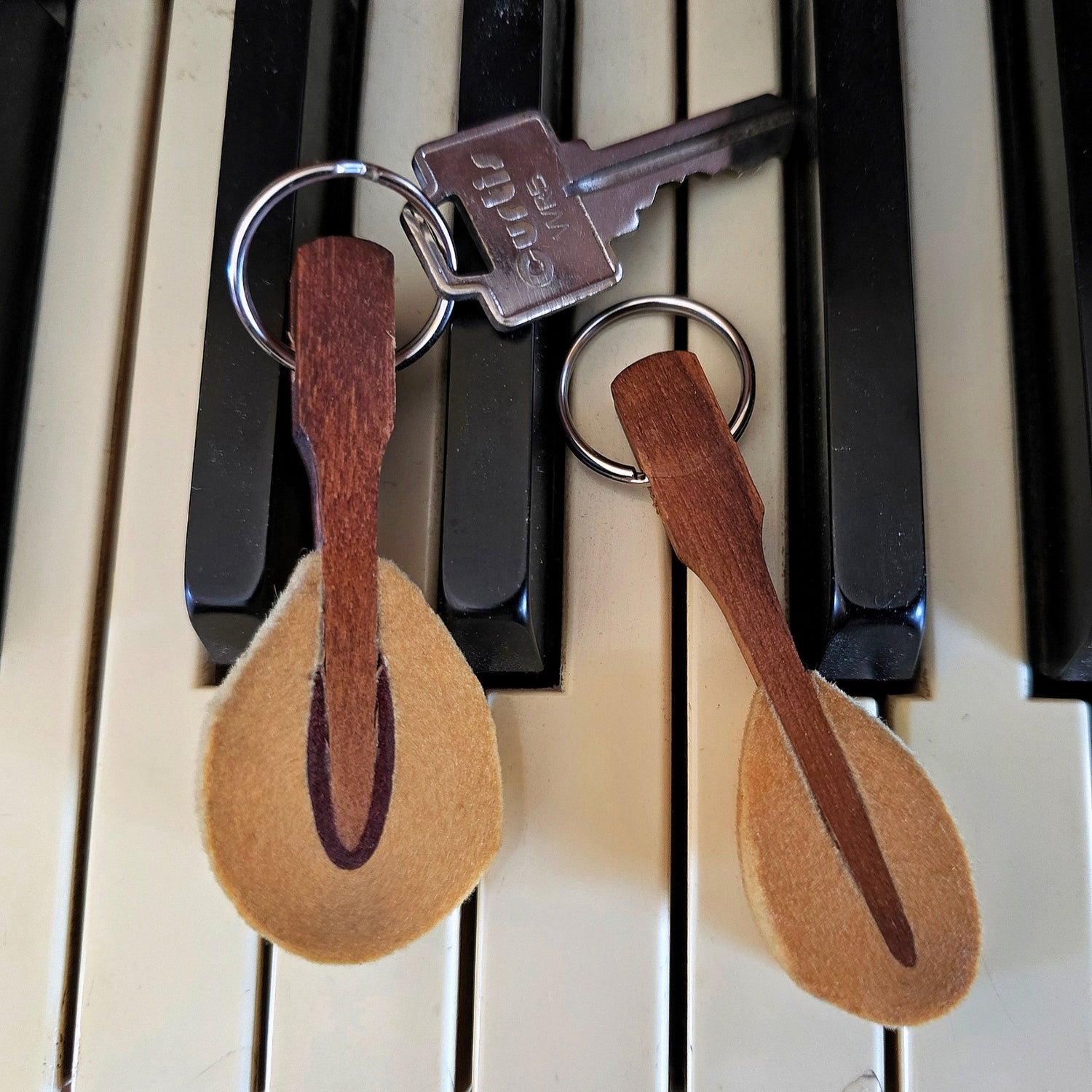 two upcycled piano hammer keychain with silver key on black and white keyboard
