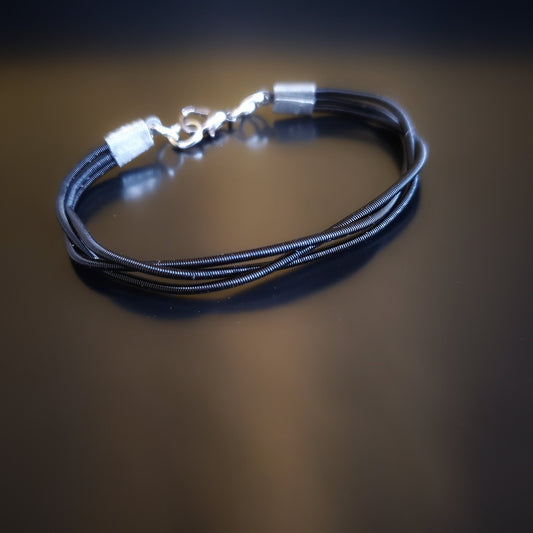 clasp style bracelet made from 3 upcycled  harp strings braided together