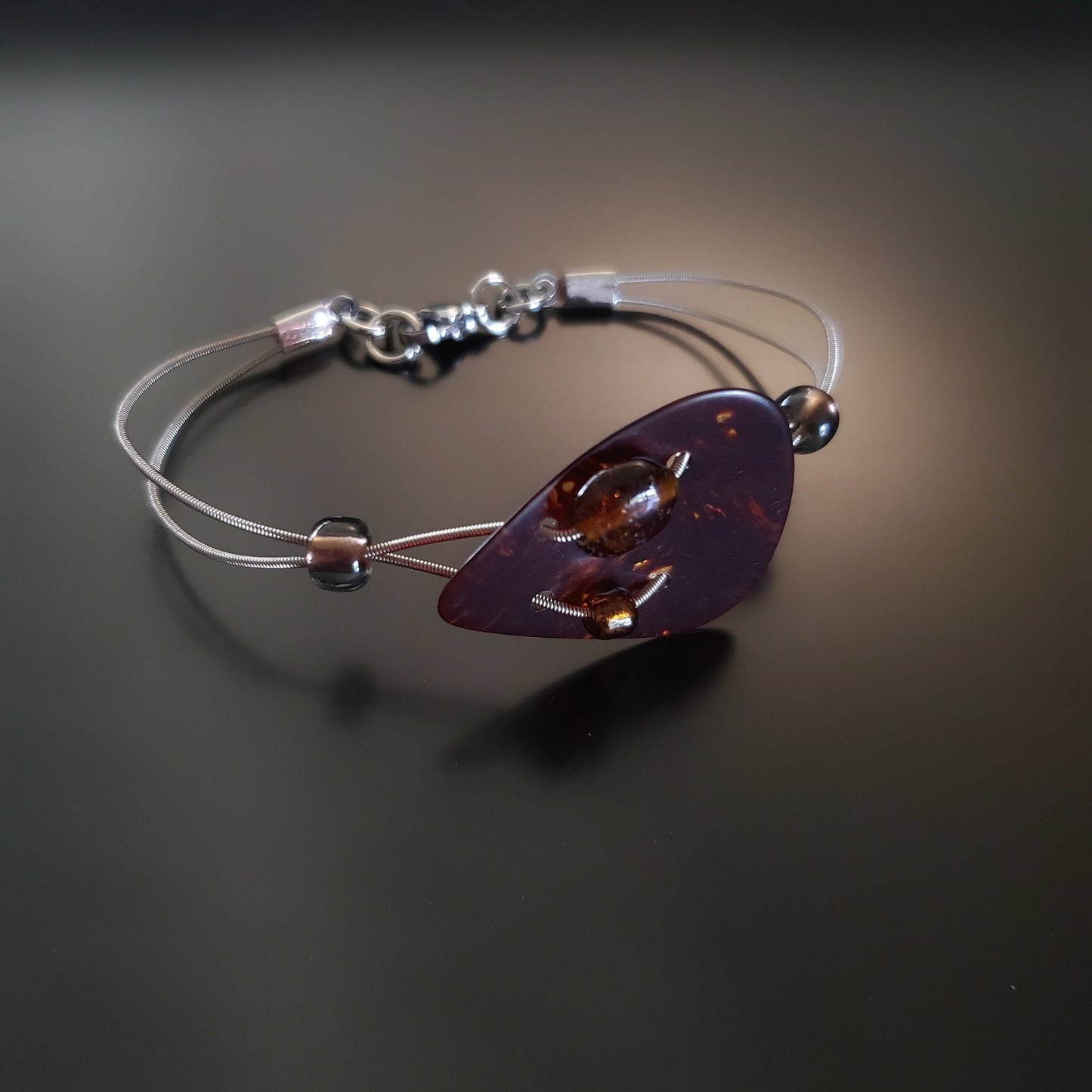 bracelet made from both upcycled guitar strings and a beautiful turtle shell brown guitar pick.