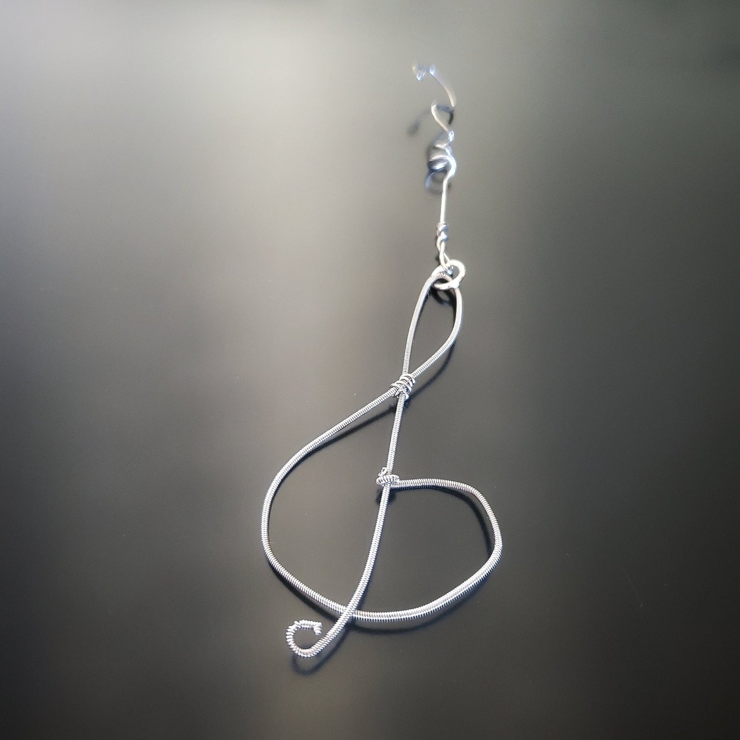 Christmas ornament in the shape of a treble clef, made from an upcycled guitar string