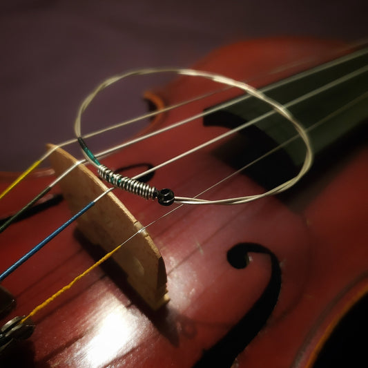 bangle style bracelet made from an upcycled violin string sitting near the bridge of a violin