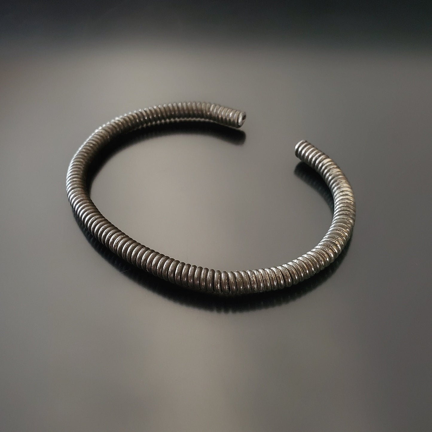 charcoal grey cuff style bracelet made from an upcycled piano string