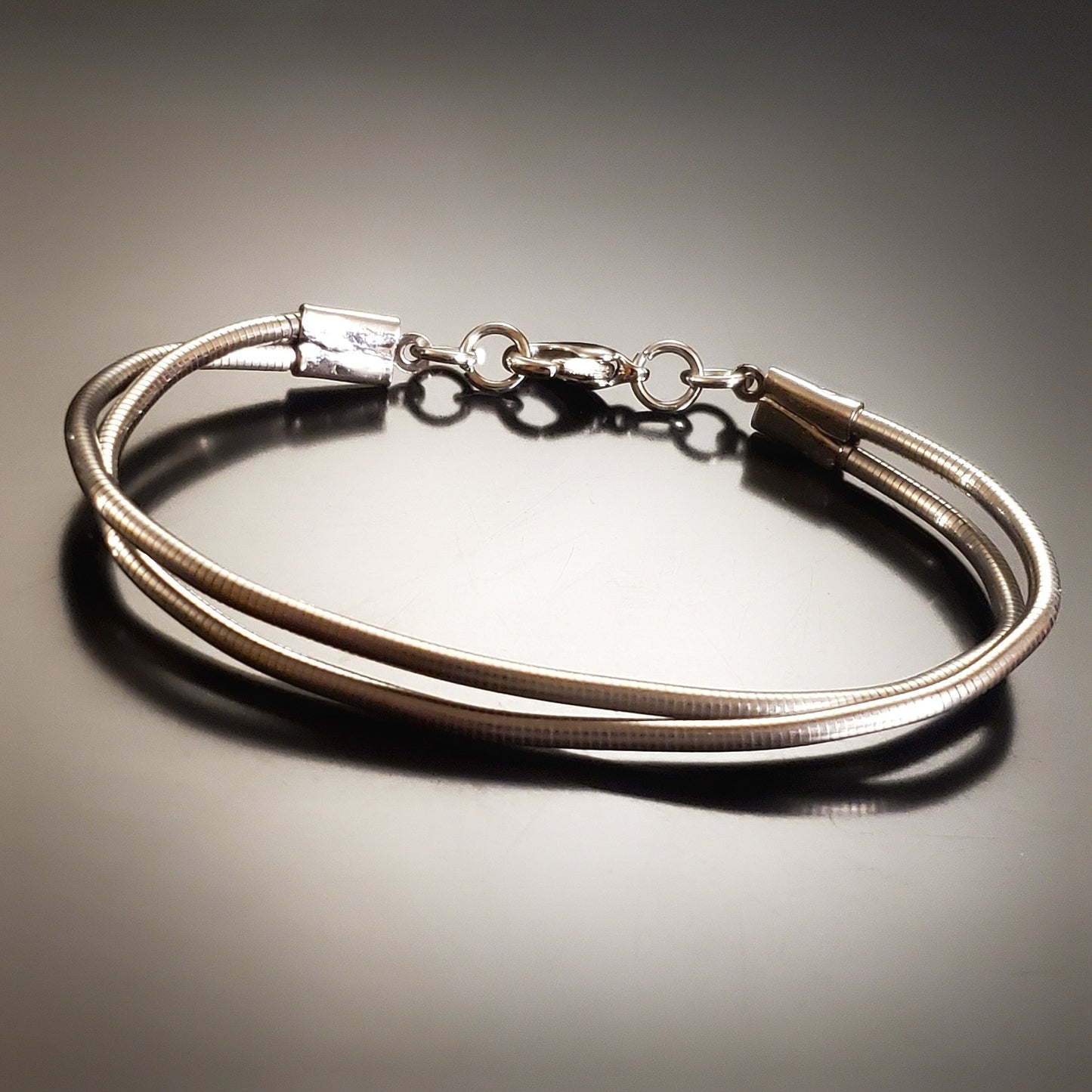 silver coloured clasp style bracelet made from upcycled upright bass strings