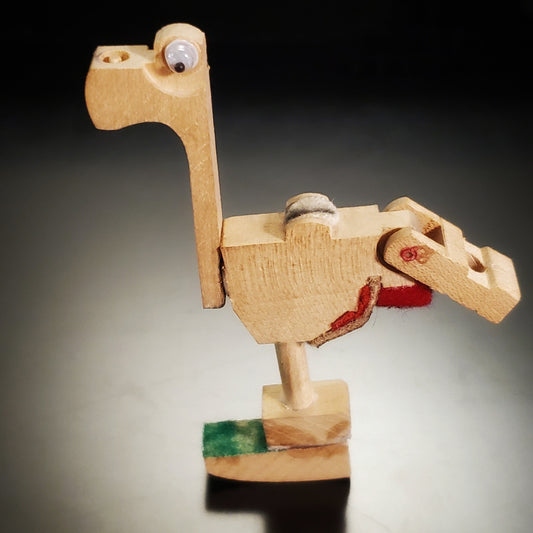 a magnet in the shape of a dinosaur-like animal made from pieces of a piano mechanism