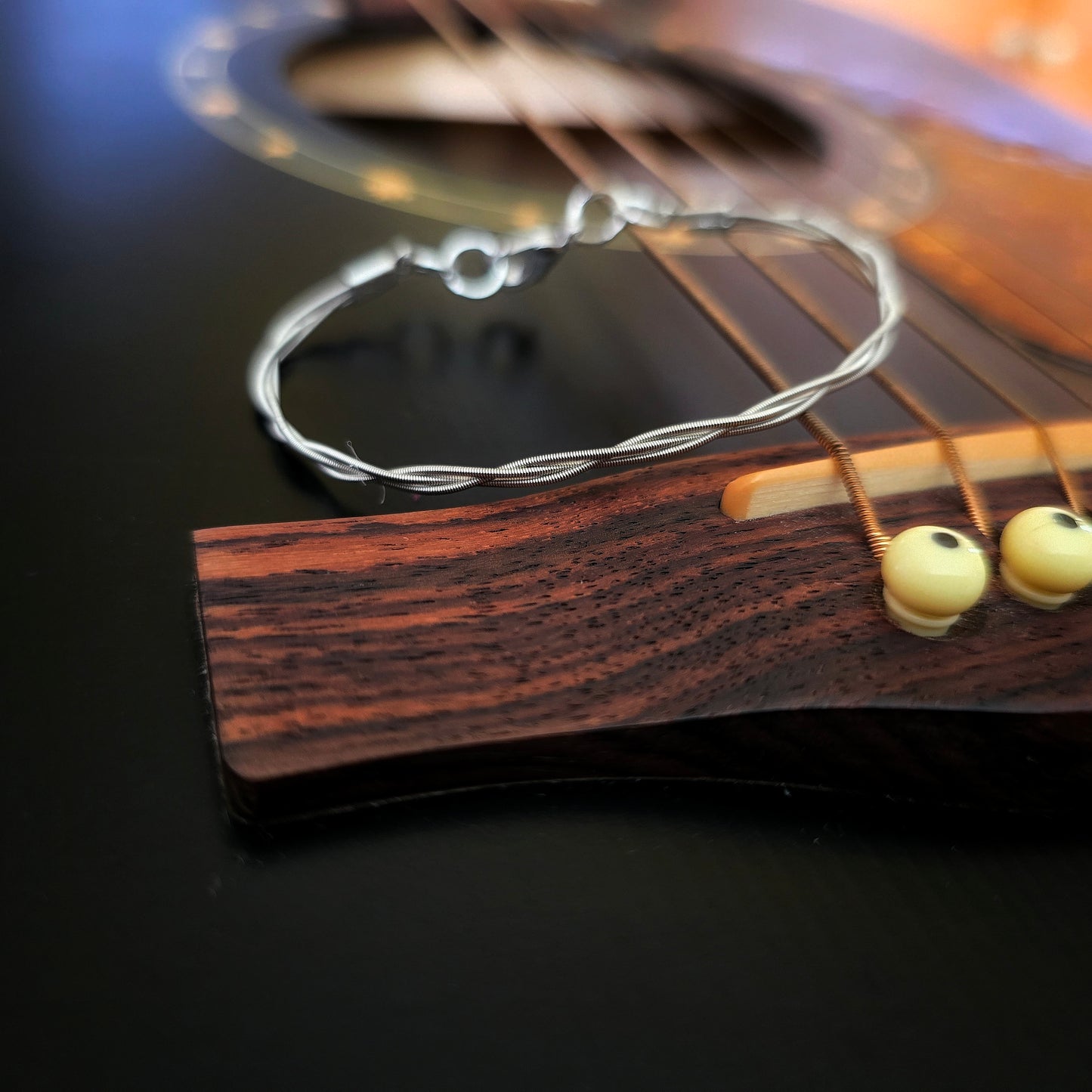 Simple upcycled guitar string braided bracelet on black guitar 