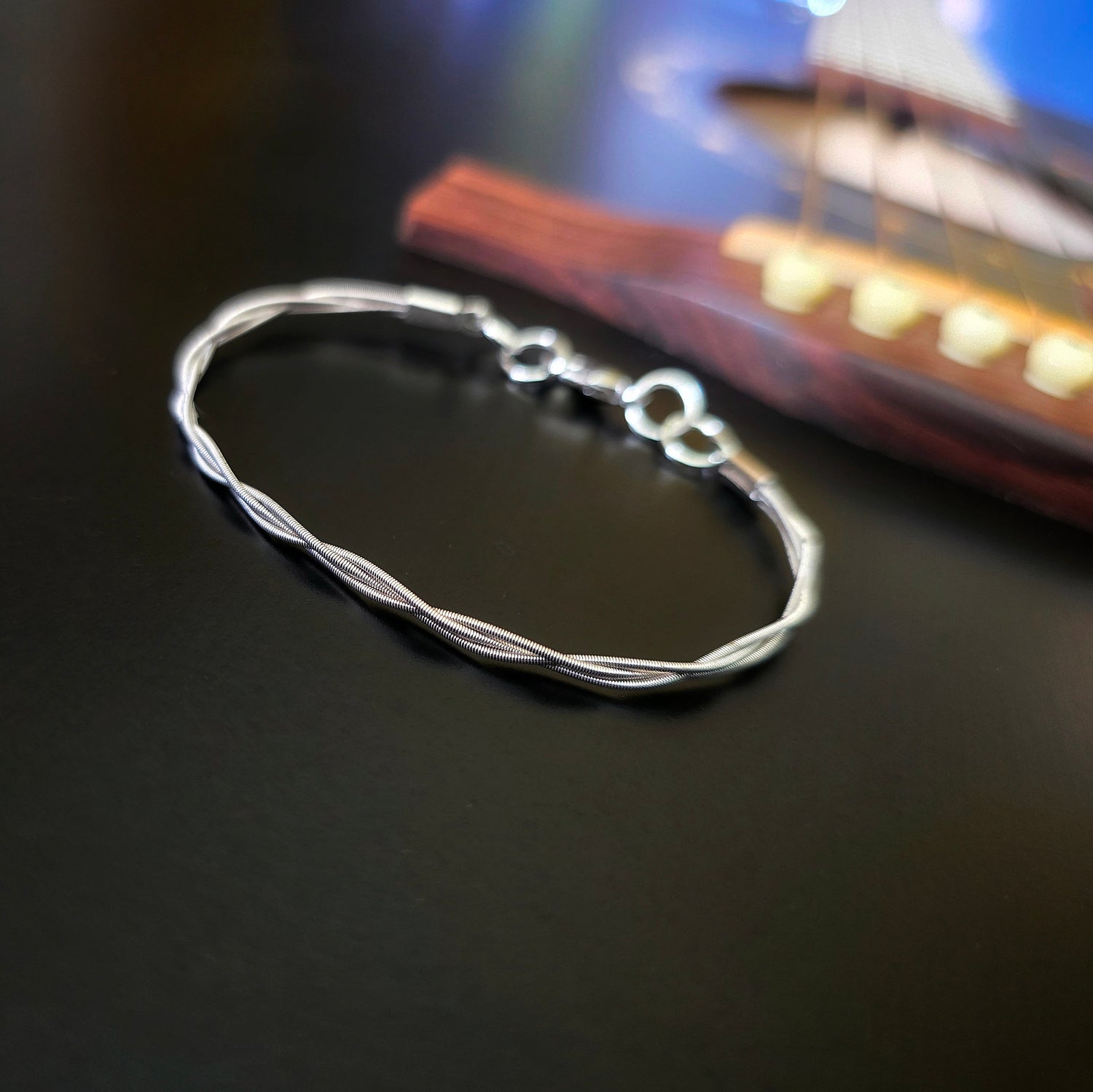 Simple upcycled guitar string braided bracelet on black guitar 