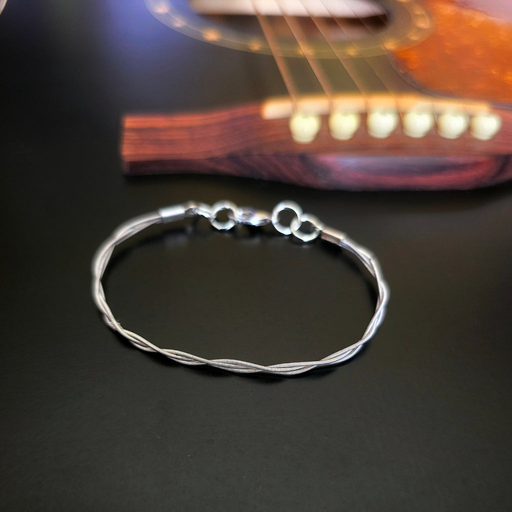Simple upcycled guitar string braided bracelet on black guitar 