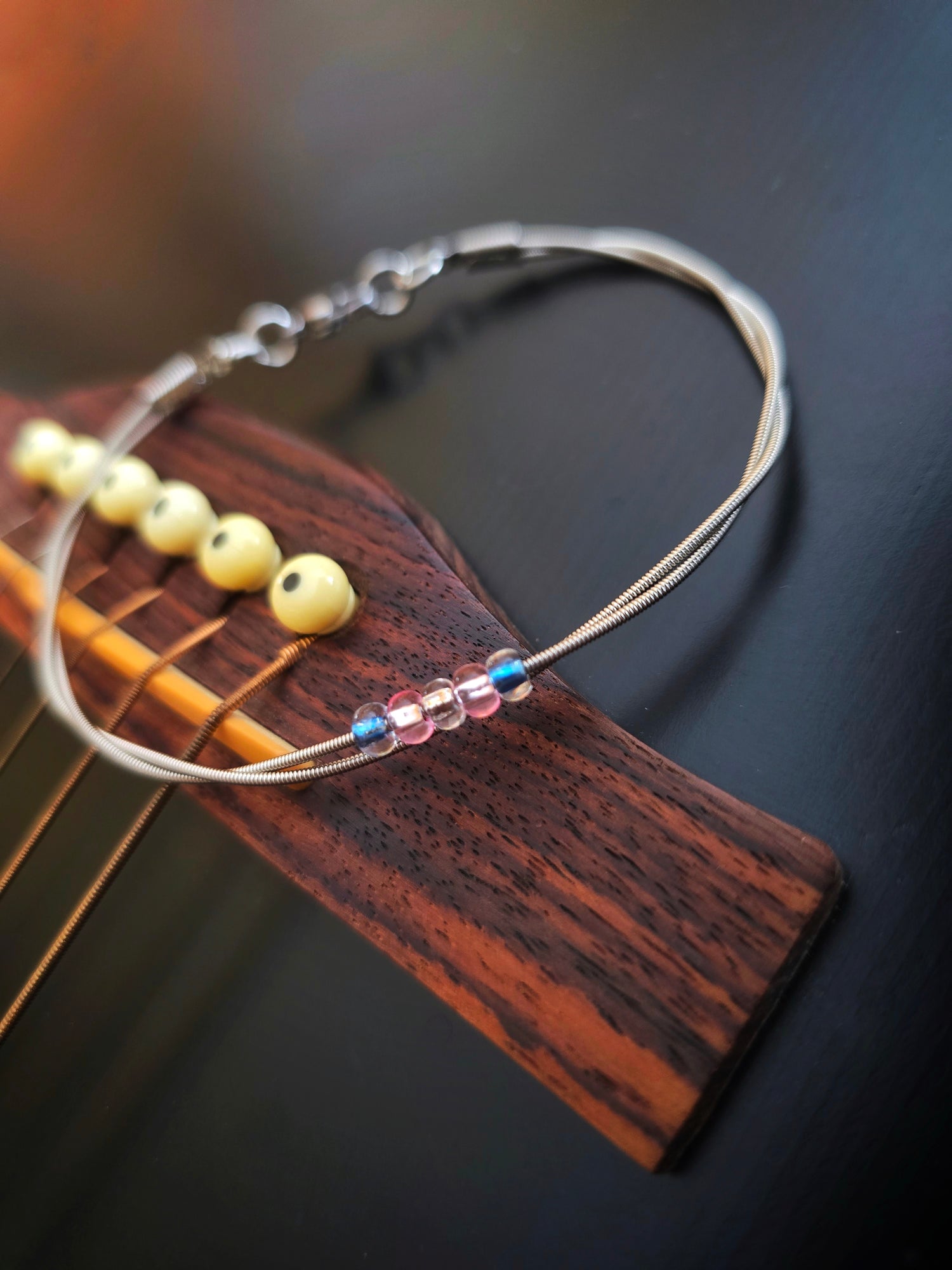 Guitar string trans pride bracelet on black guitar 