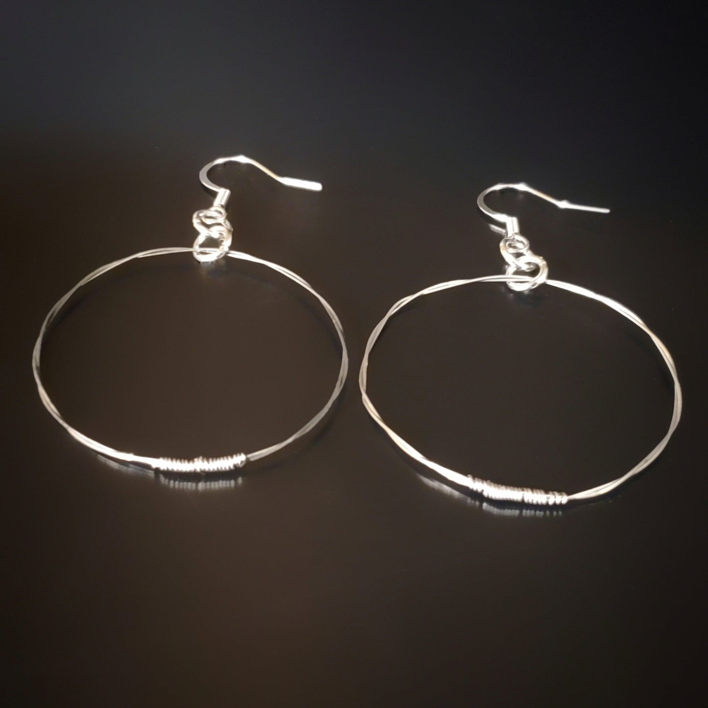 silver coloured hoop style earrings made from upcycled guitar strings 