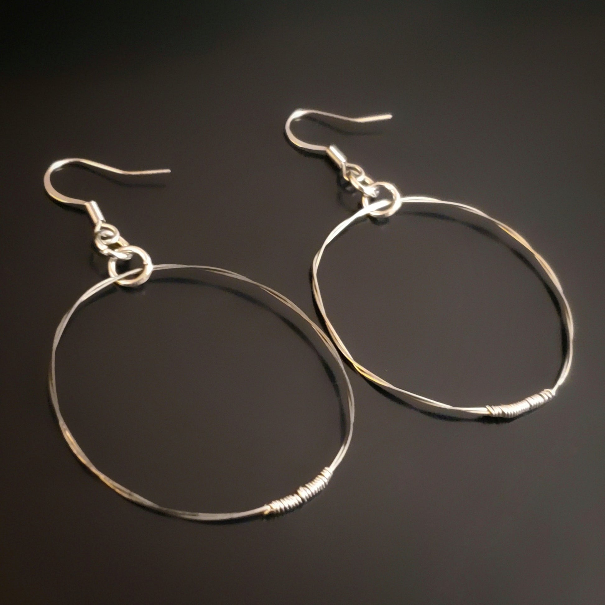 silver coloured hoop style earrings made from upcycled guitar strings 