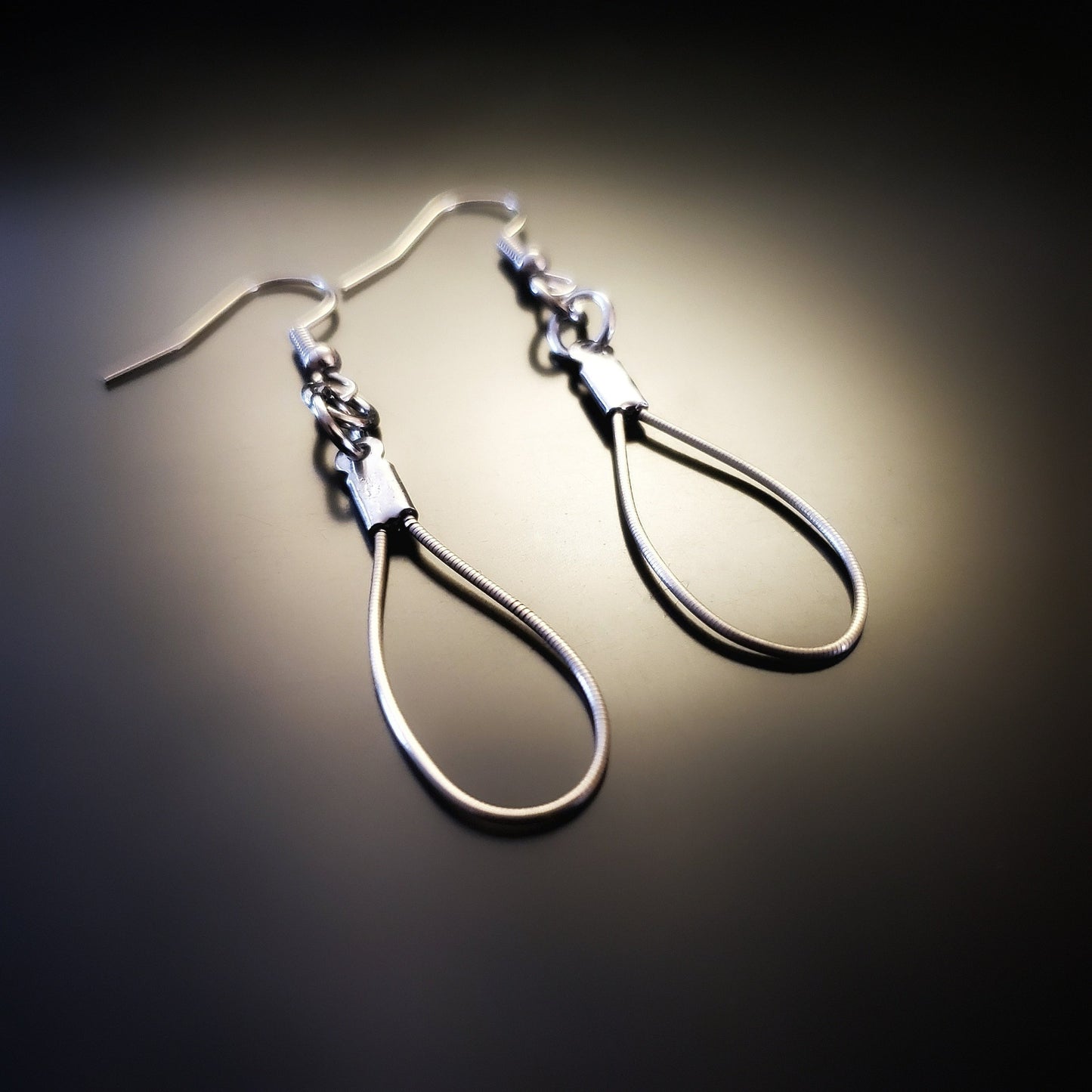 a pair of teardrop style earrings made from upcycled violin strings