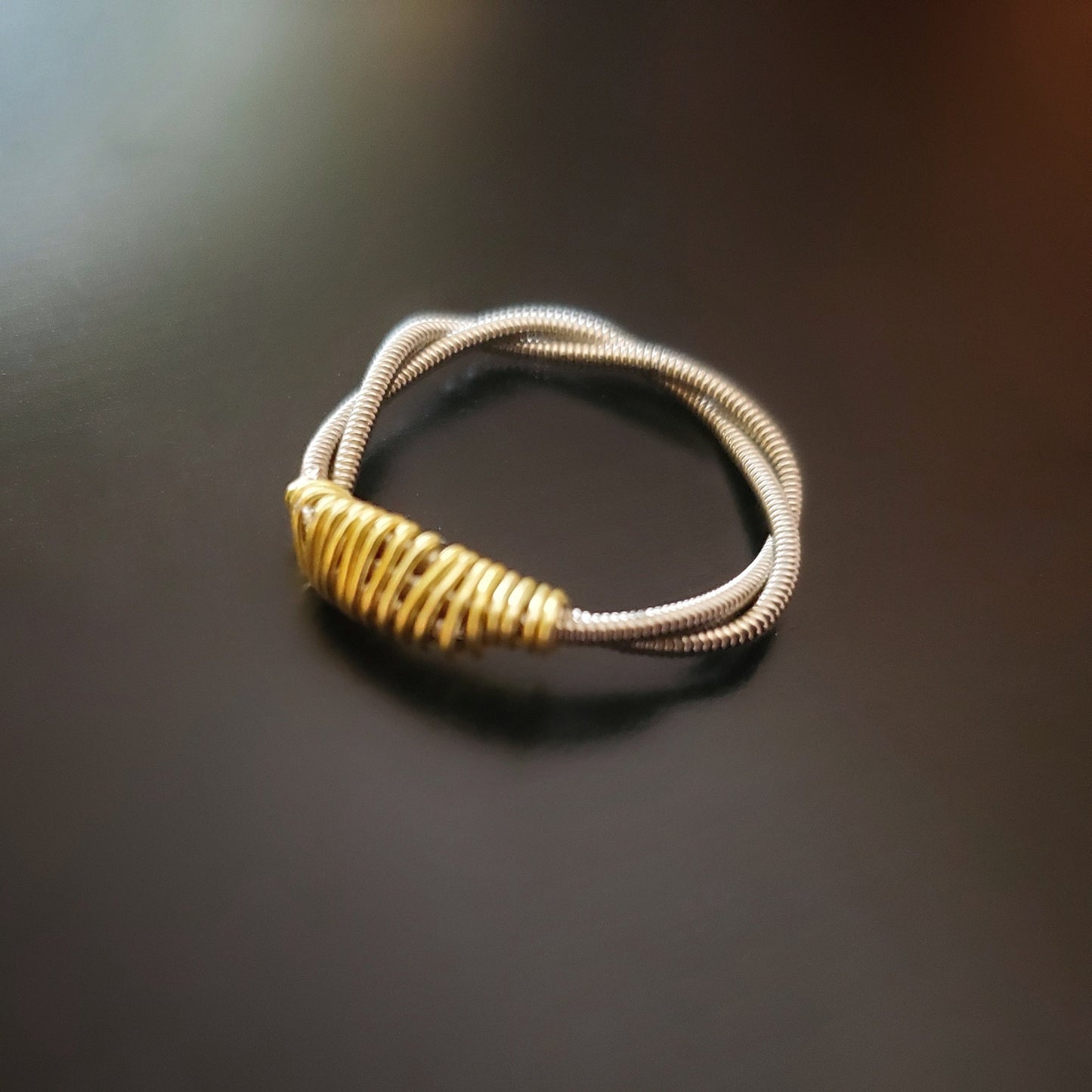 silver coloured guitar string ring with gold coloured wire