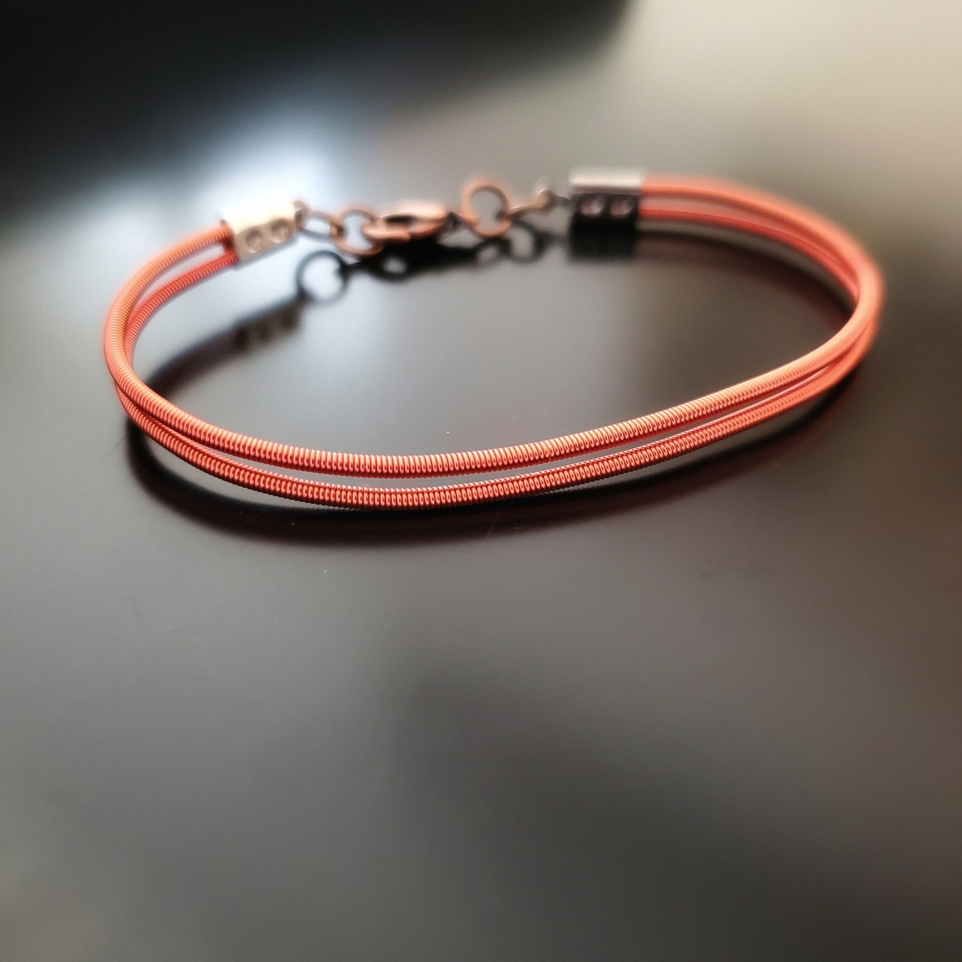clasp style bracelet made from orange upcycled harp strings