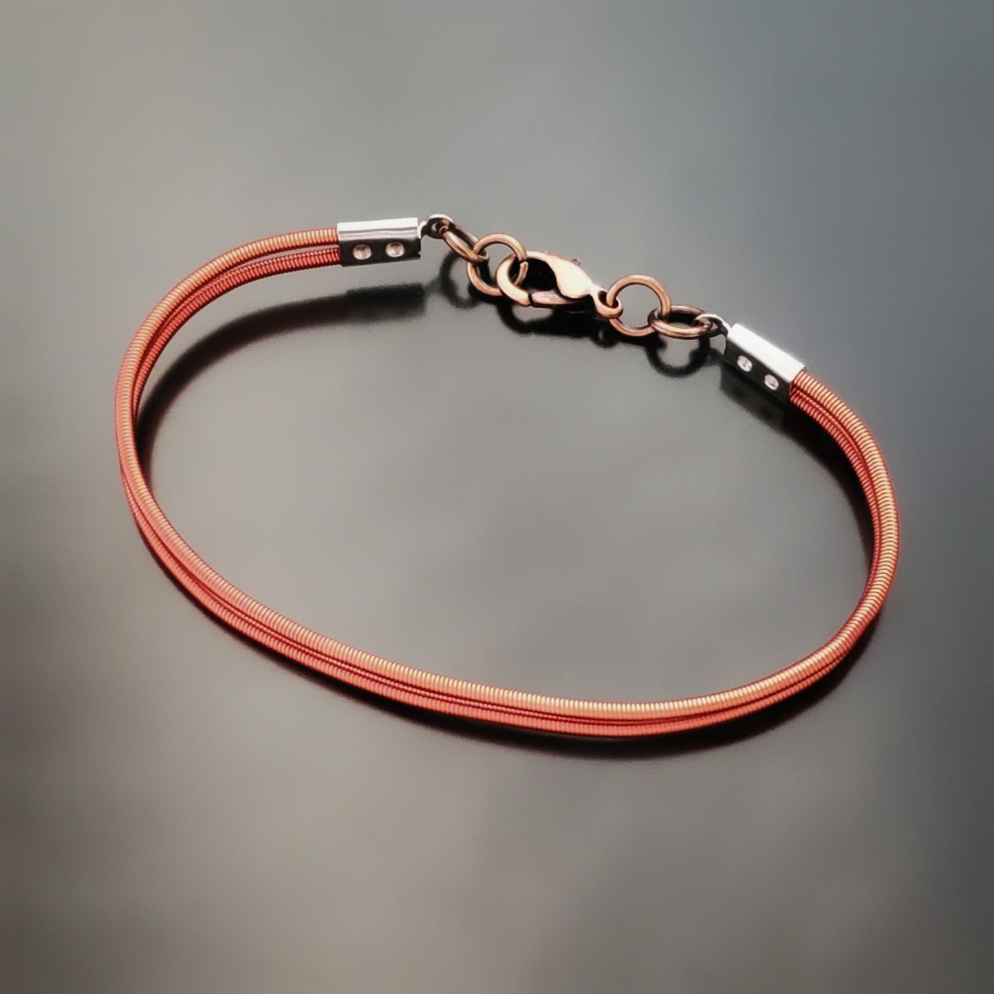 clasp style bracelet made from orange upcycled harp strings