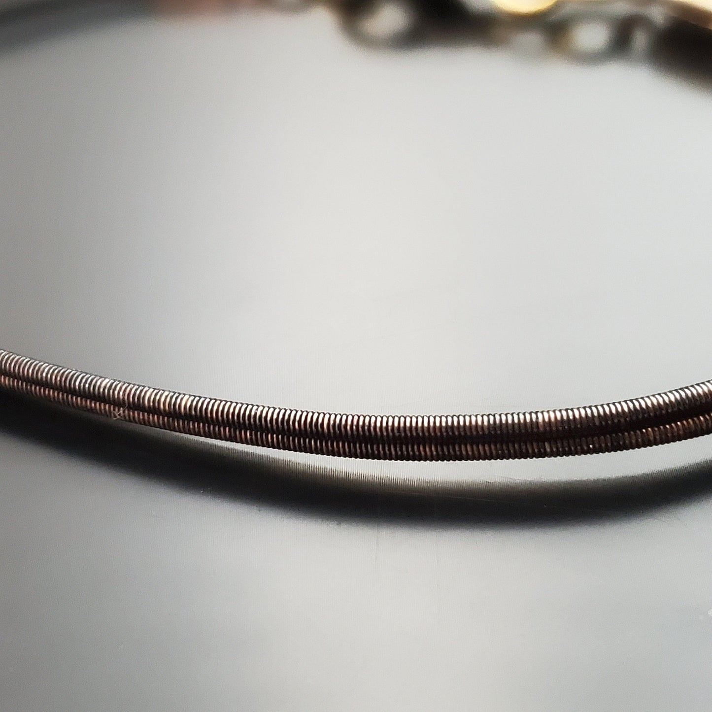 close-up of a brown clasp style bracelet made from an upcycled harp string