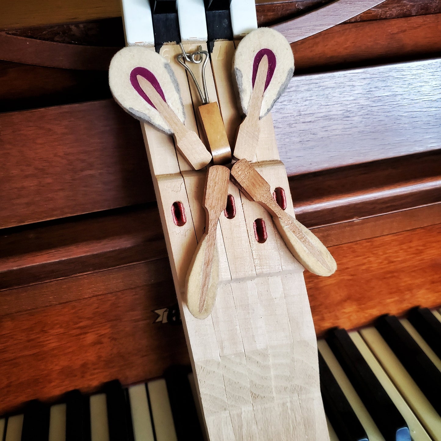 close-up of a key holder made from 5 upcycled piano keys on the keyholder is a butterfly design made from piano keys and other parts - the key holder is sitting on a piano keyboard