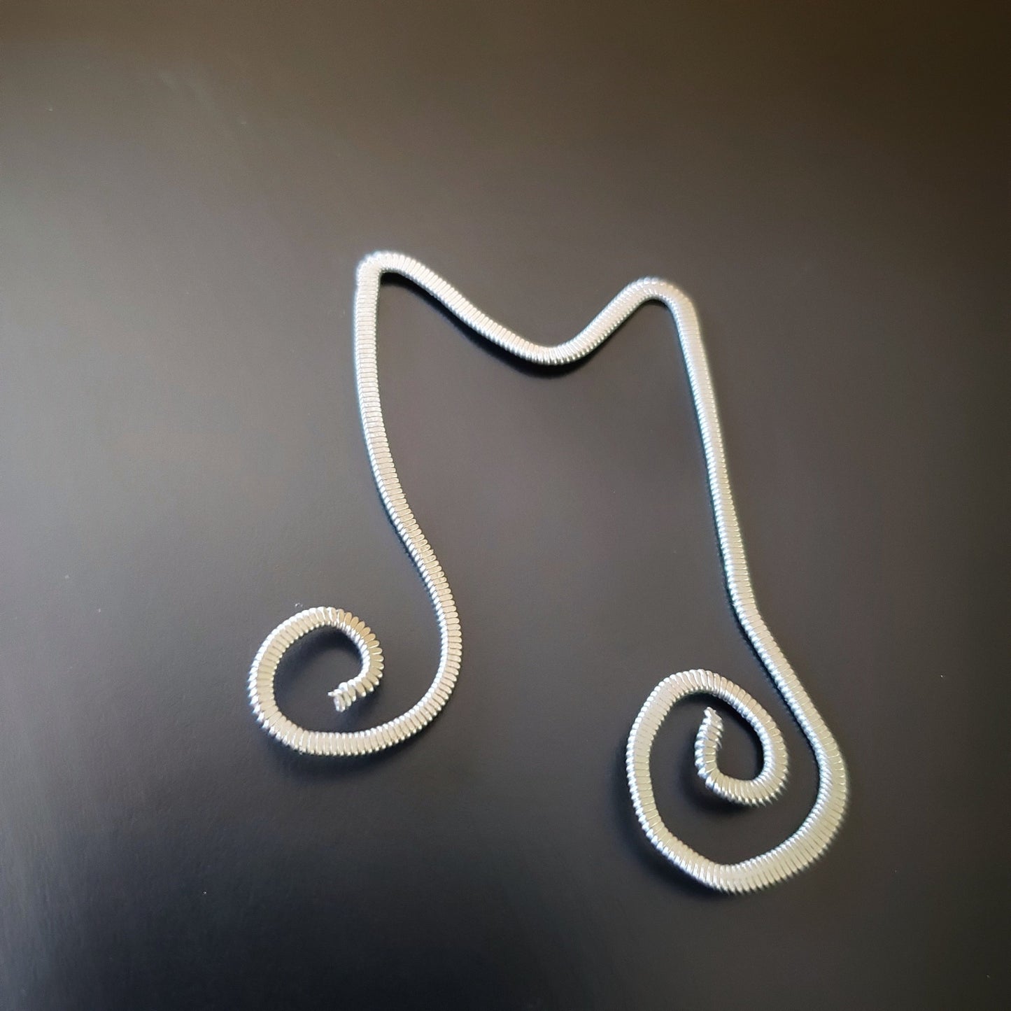 bookmark shaped like a double quarter note made from a hammered guitar string 