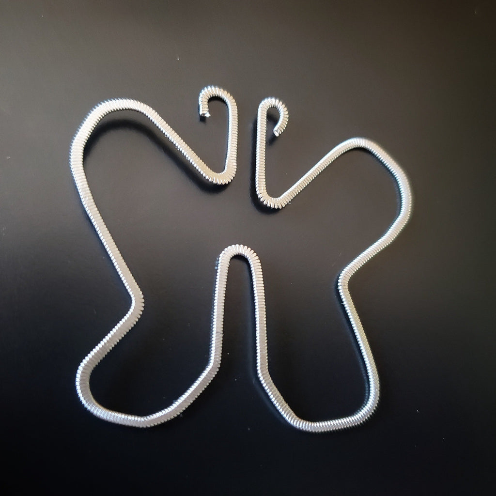 a bookmark made from an upcycled guitar string which was hammered flat and shaped into a butterfly - bookmark sits a black background