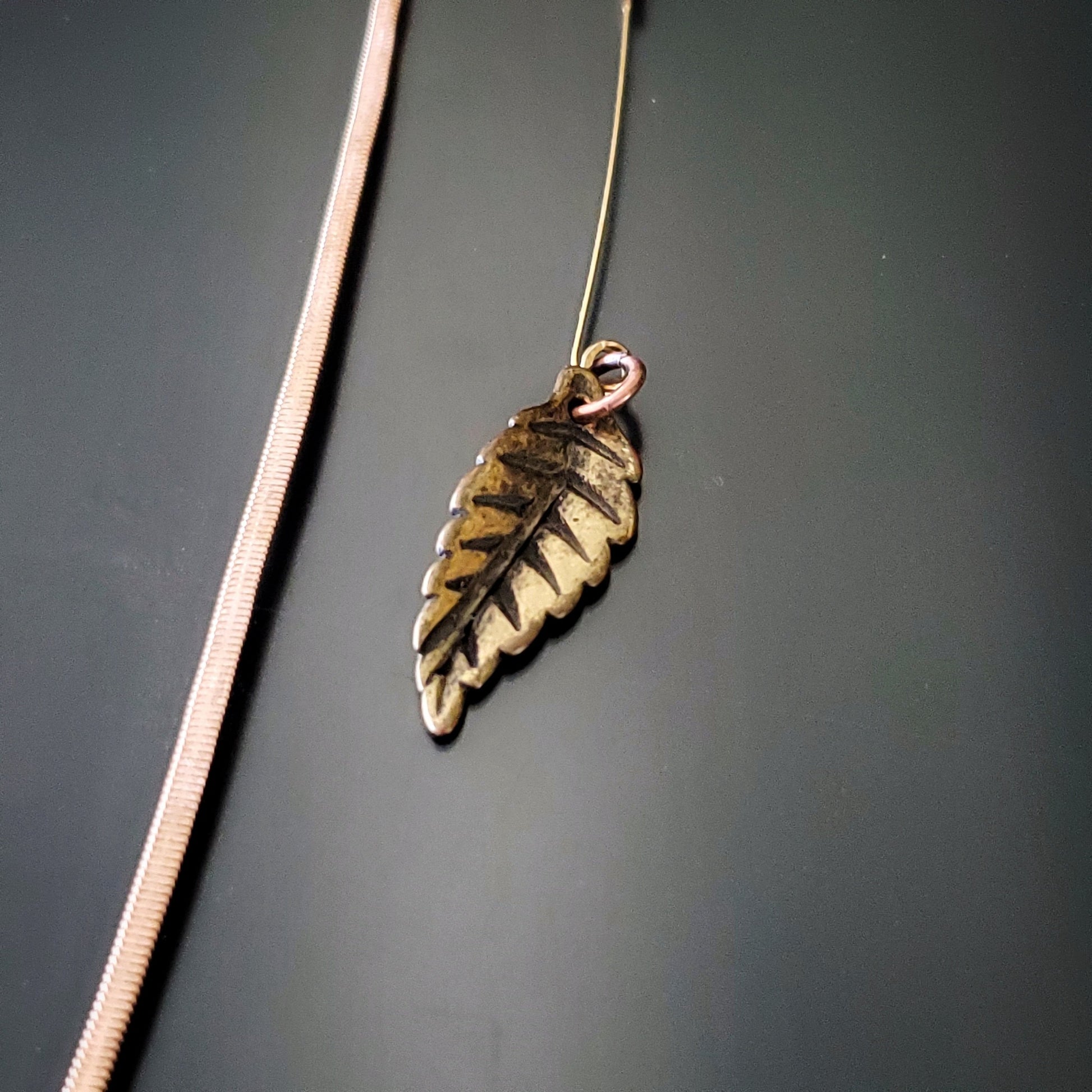 close-up of a hook style bookmark made from an upcycled guitar string and a leaf shaped charm