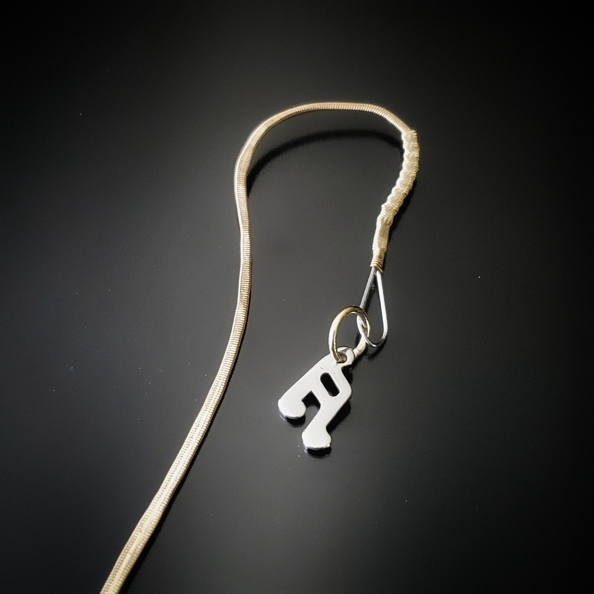 close-up of a hook style bookmark made from an upcycled mandolin string and a silver quarter note shaped charm