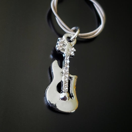 close-up of a silver coloured keychain made from an upcycled guitar string - on it hangs a silver coloured electric guitar