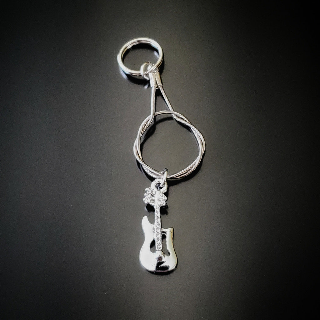 silver coloured keychain made from an upcycled guitar string - on it hangs a silver coloured electric guitar