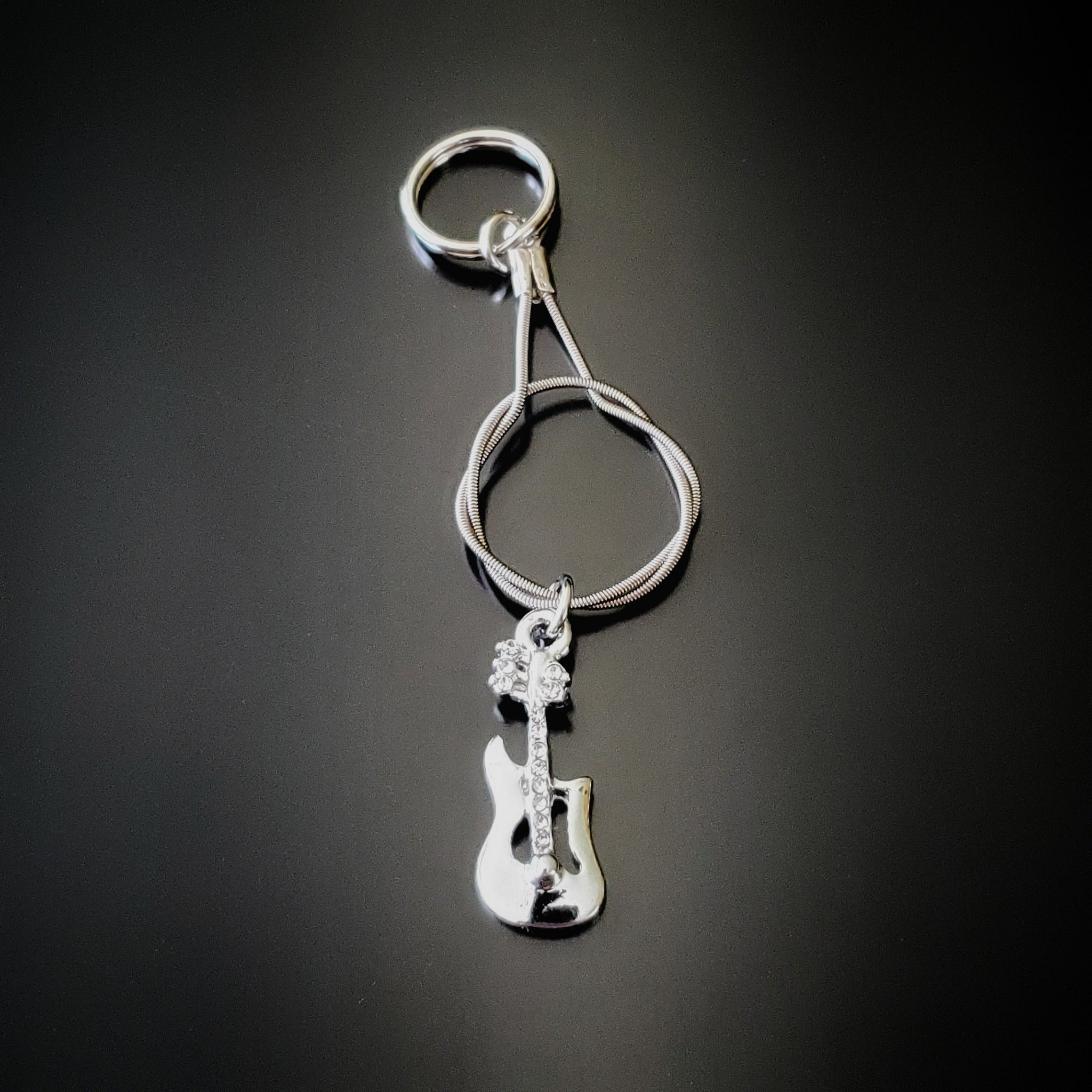 silver coloured keychain made from an upcycled guitar string - on it hangs a silver coloured electric guitar